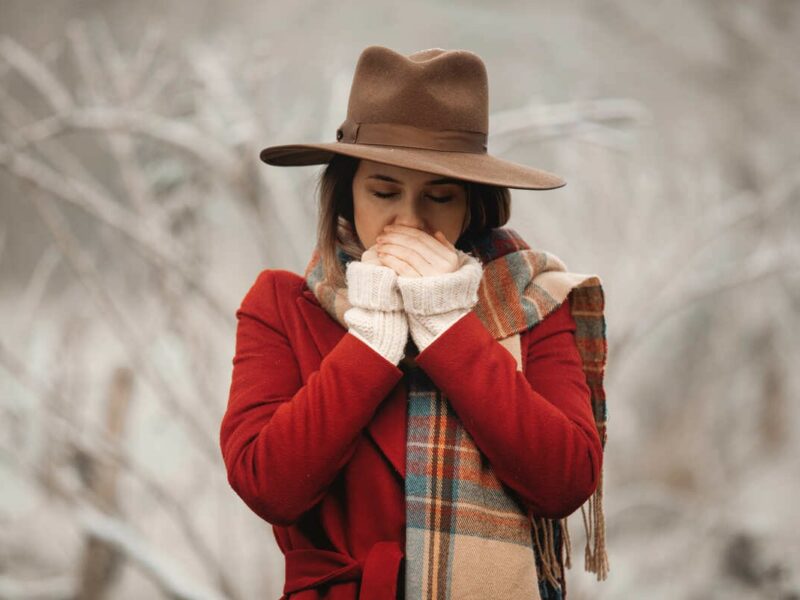 Woman in hat and red coat in winter countryside